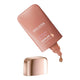 Weleda Sunkissed Bronzing Serum Drops in a metallic rose gold squeeze bottle with its cap removed and a single drop dripping from the tip.