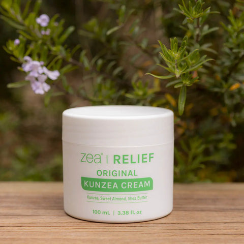 Jar of Zea Relief Kunzea Cream on a wooden surface with plants in the background