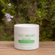 Jar of Zea Relief Kunzea Cream on a wooden surface with plants in the background
